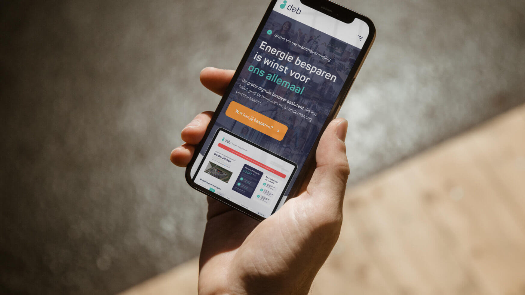 Een persoon houdt een smartphone vast met daarop een website over energiebesparing.