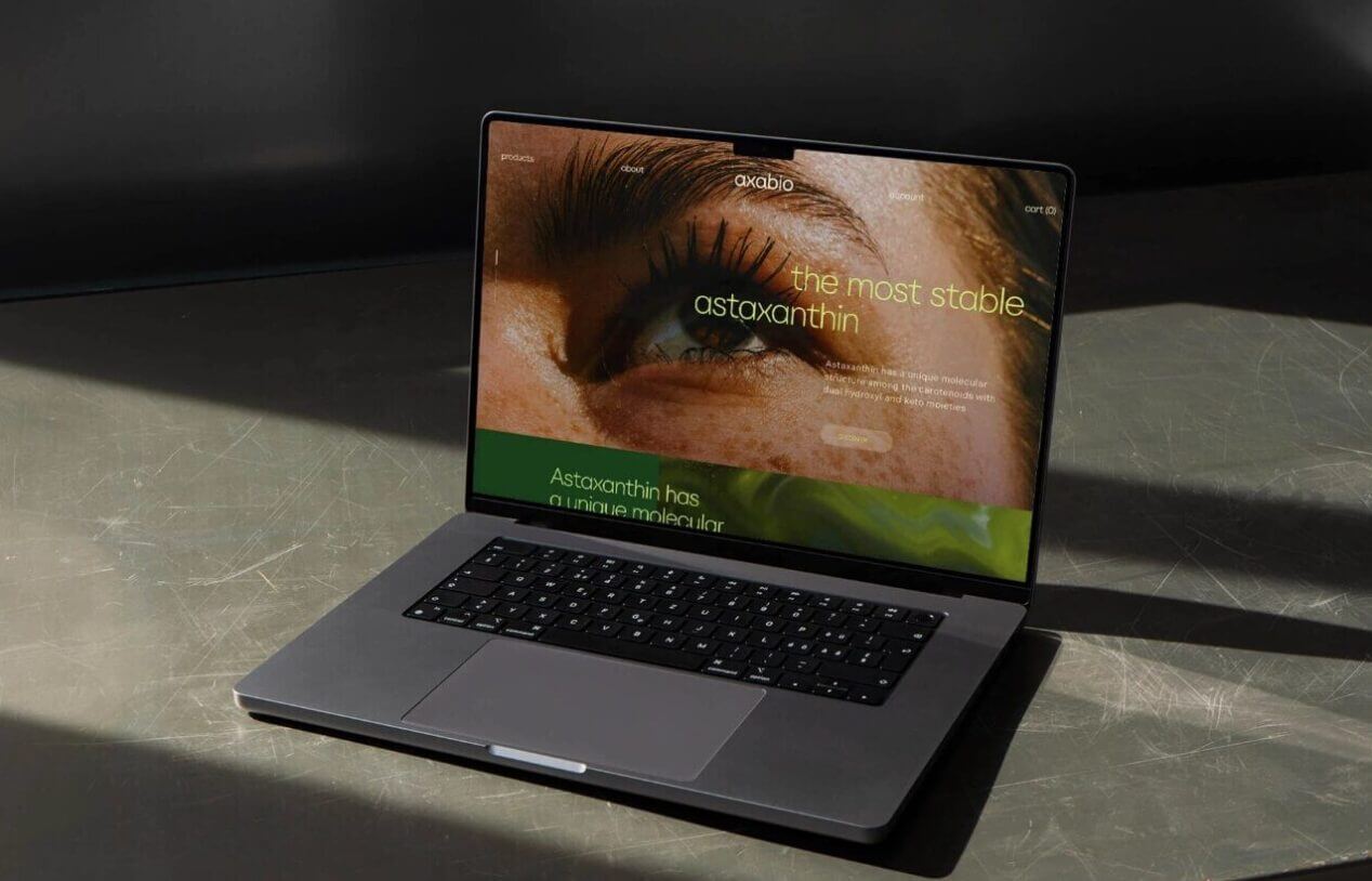 Laptop op een schaduwrijk bureau met daarop een webpagina over astaxanthine, een oogafbeelding en tekst.