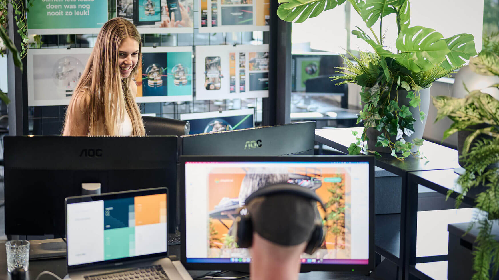 In een levendige, groene ruimte werken een man en een vrouw geconcentreerd aan hun computers in de creatieve omgeving van Playdome.