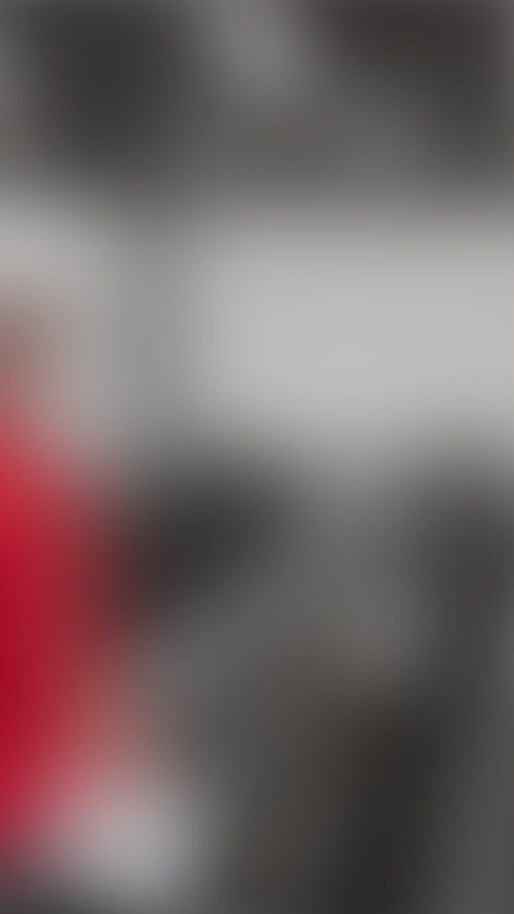 Onscherpe foto: persoon in rood shirt bij de toonbank, grijze achtergrond.