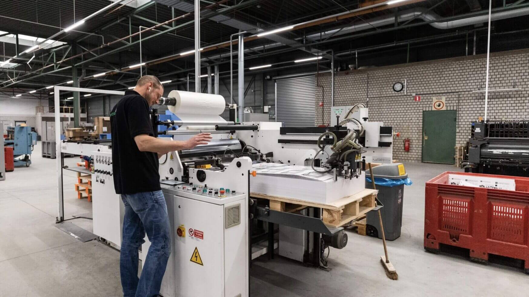 Fabrieksarbeider bedient een enorme drukmachine.