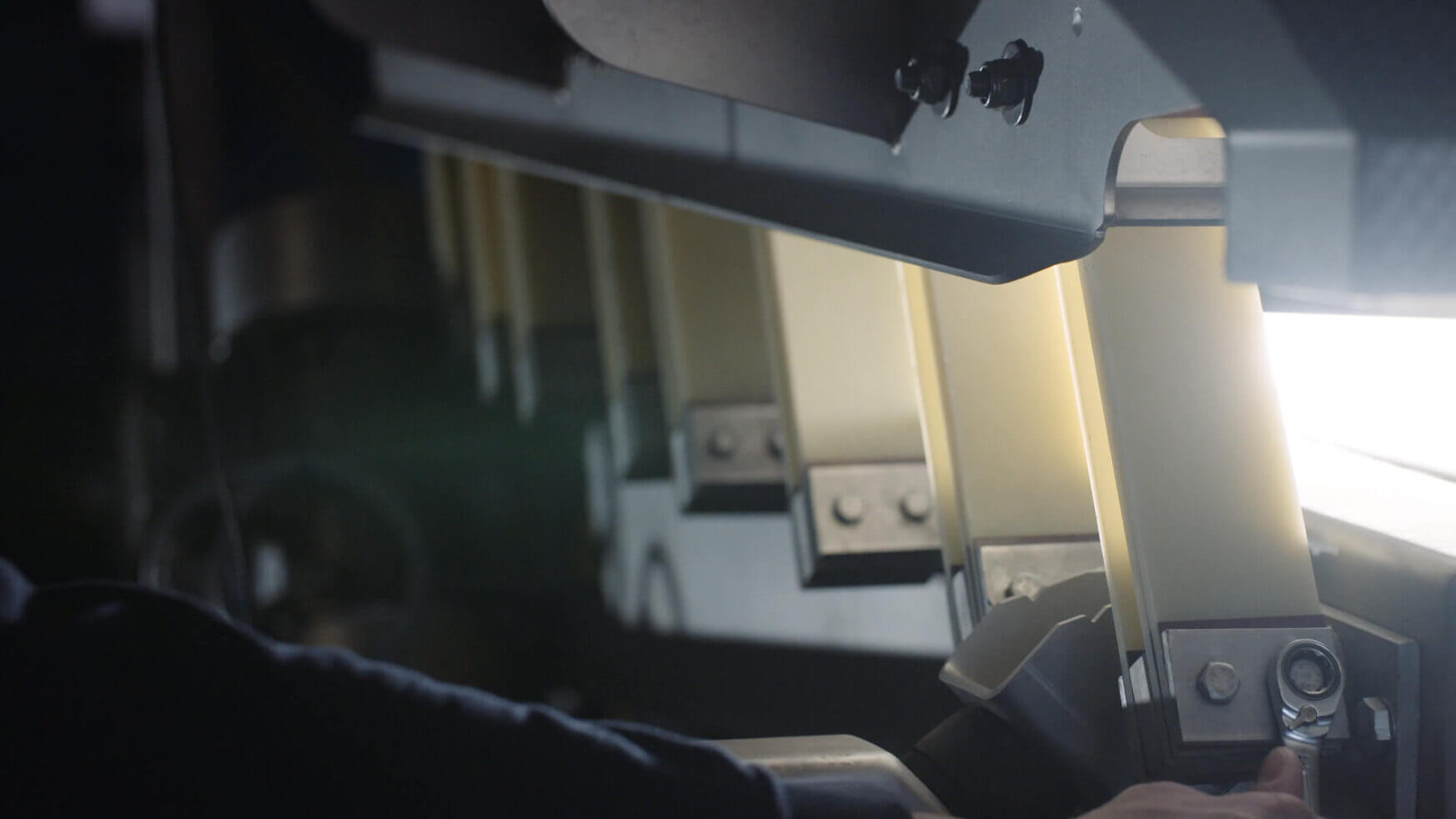 Close-up: persoon die industriële machines bij zacht licht afstelt.