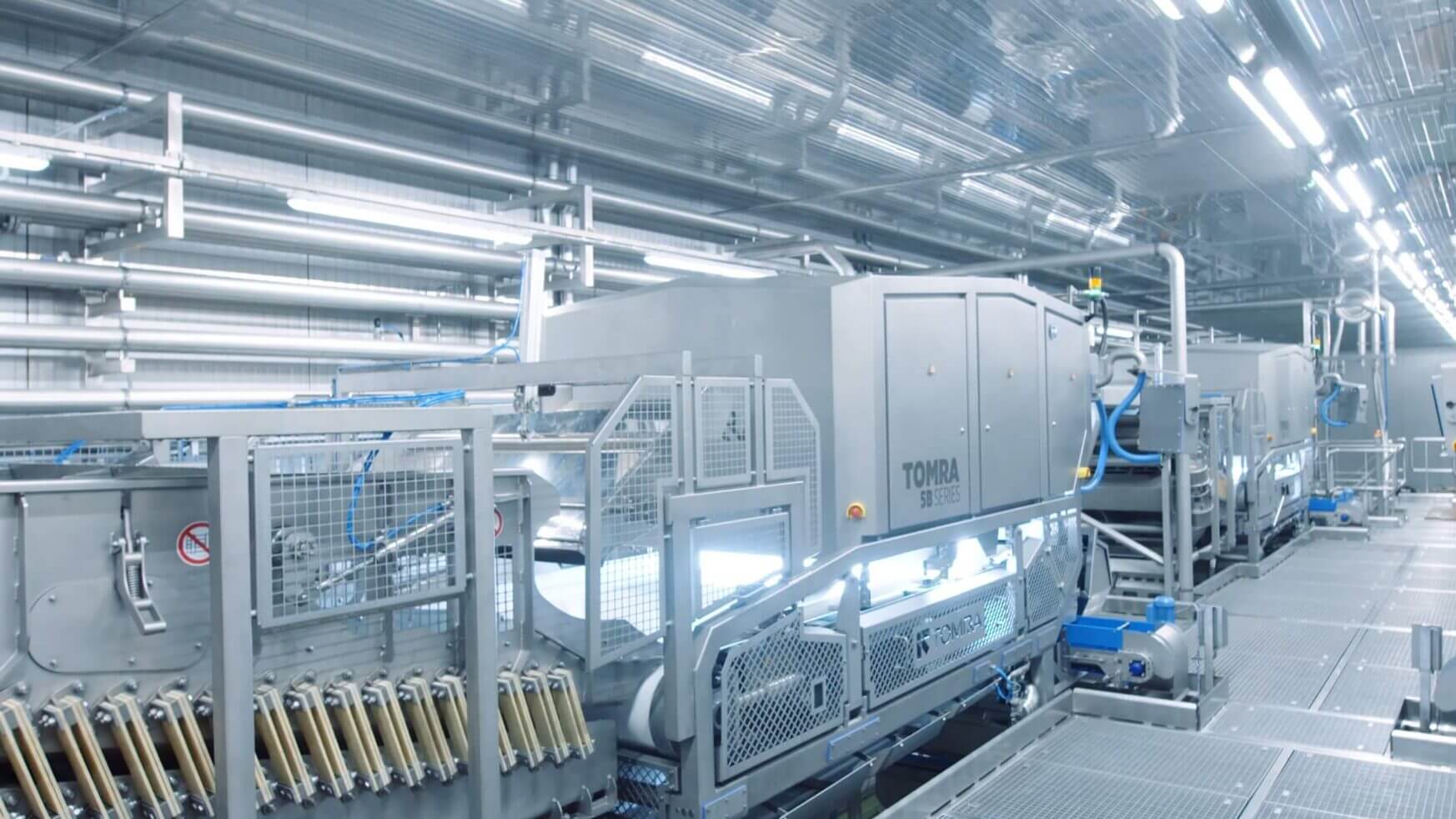 Moderne fabriek: ingewikkelde machines, metalen buizen en tandwielen verlicht door felle plafondlampen.