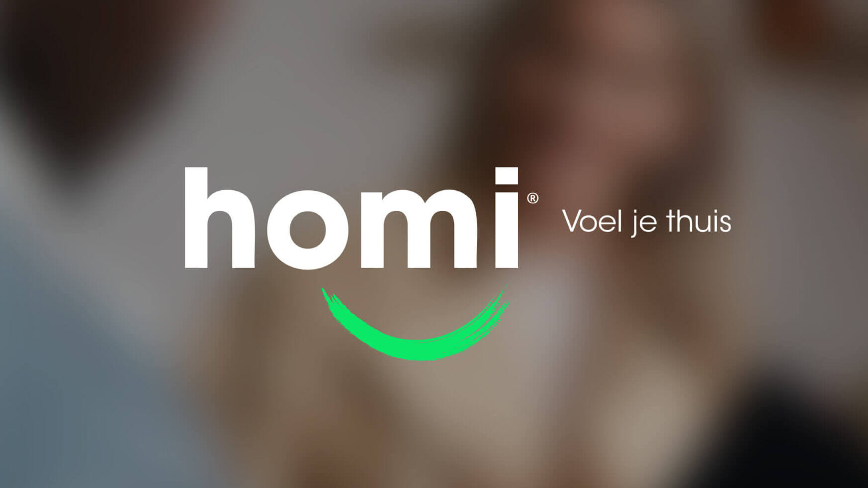 Logo: "homi" & "Voel je thuis", groene glimlach, onscherpe achtergrond.