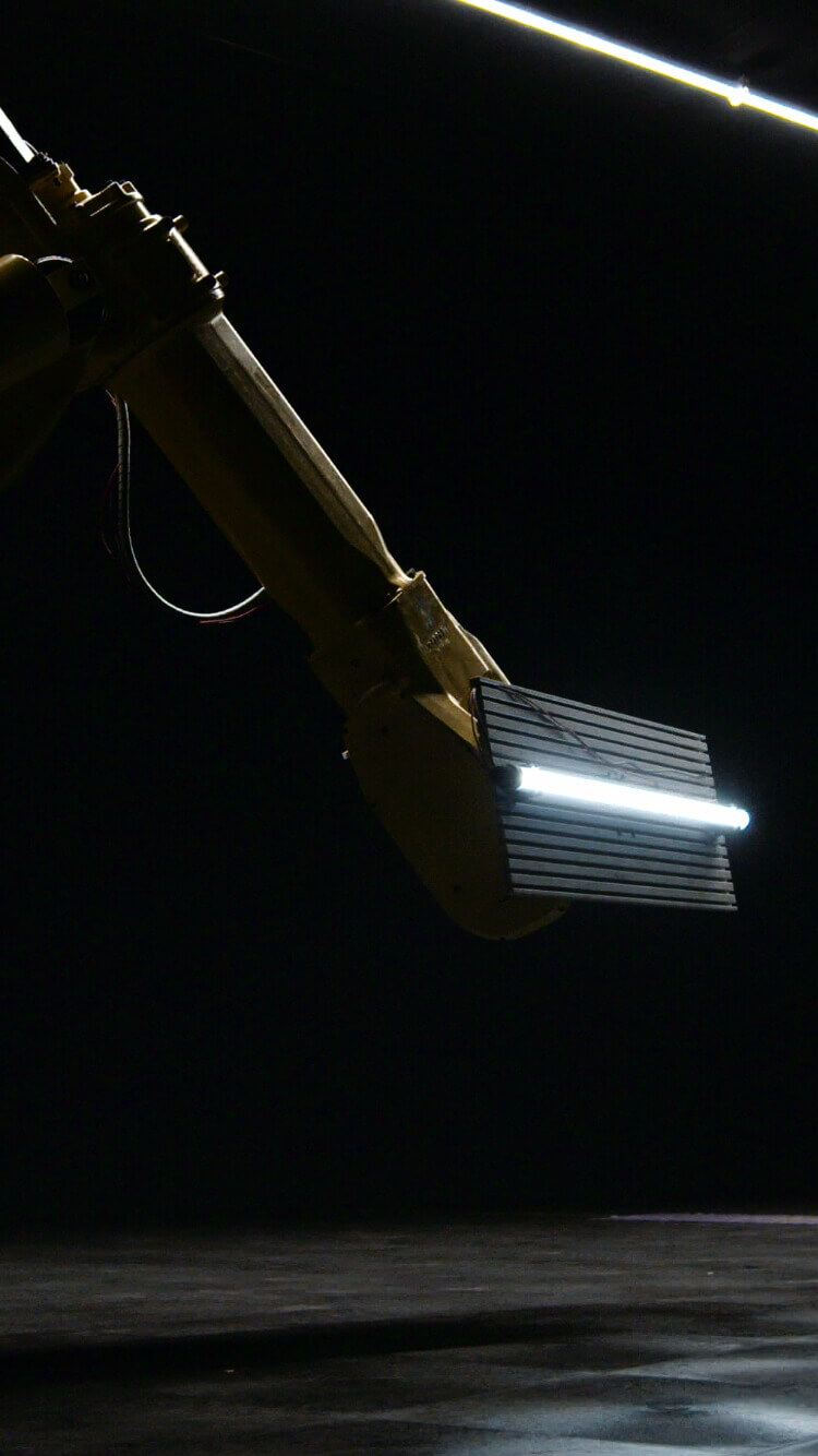 Robotarm in het donker grijpt een rechthoek vast met een heldere horizontale lijn.