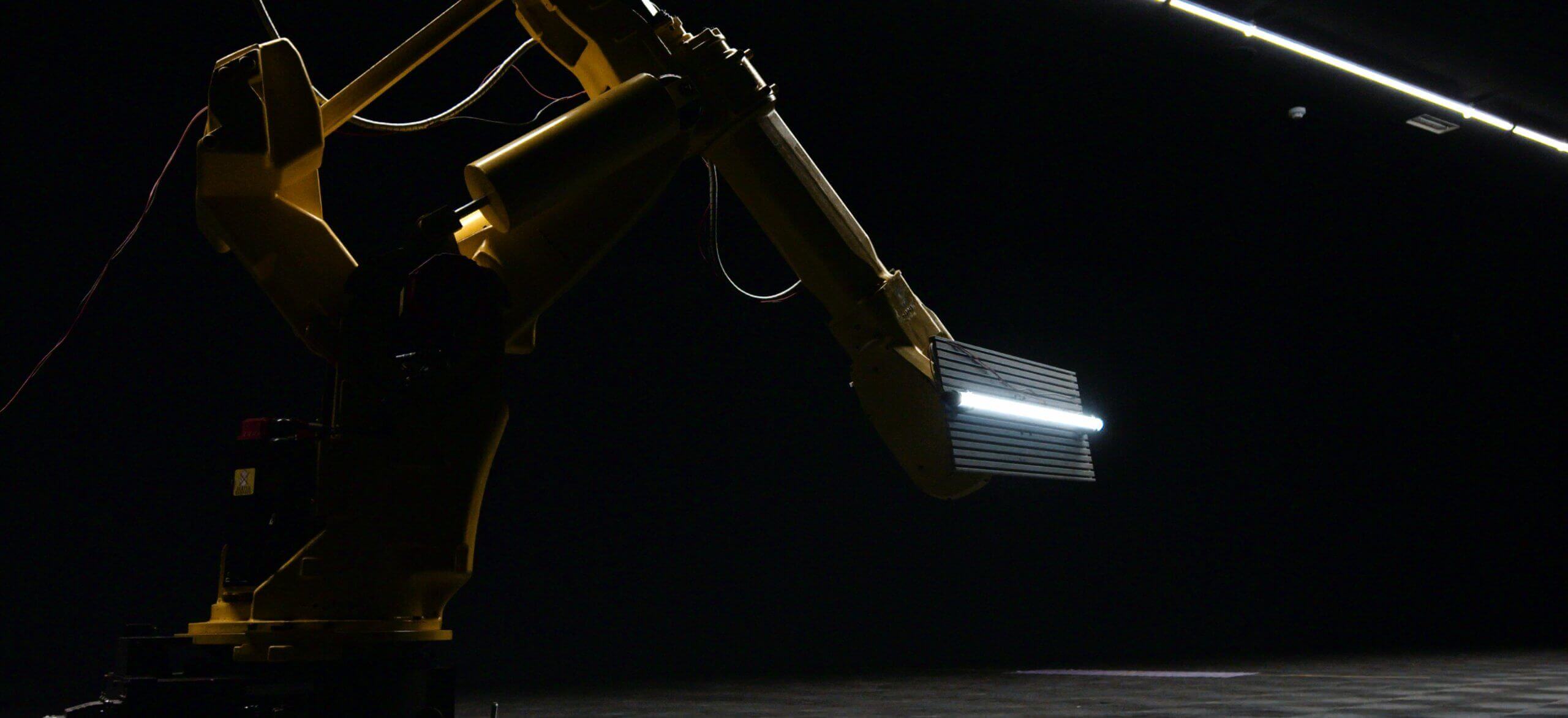 Een gele robotarm met licht gloeit in het donker.