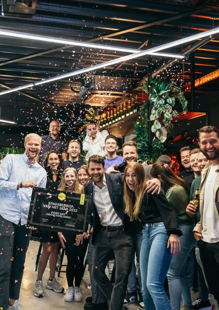 Feestvibes! Confetti regent terwijl blije gezichten een bord omhoog houden in een bruisende locatie. 🥳✨.