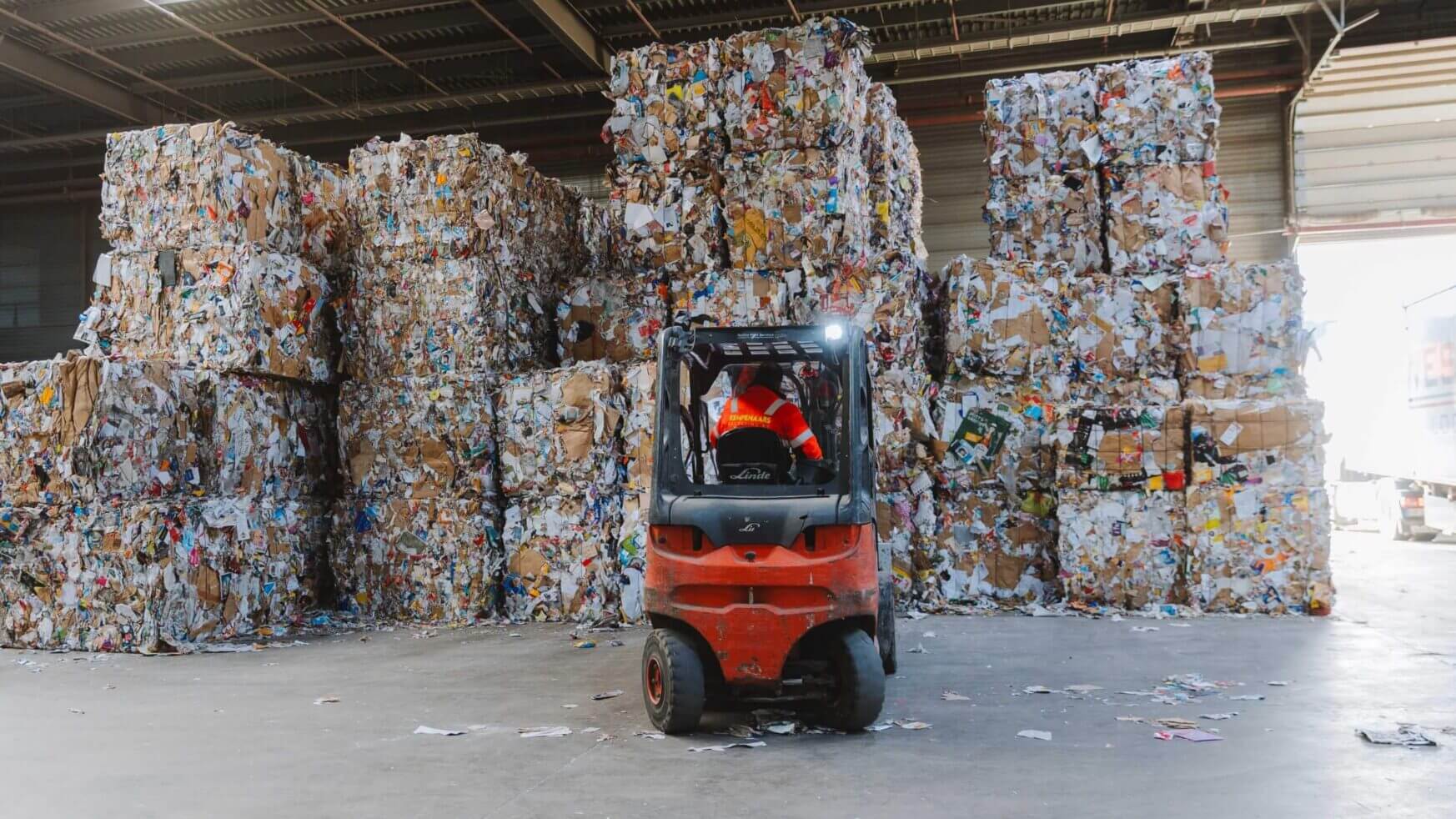 Vorkheftruck vervoert gecomprimeerde recyclebare materialen in het magazijn.