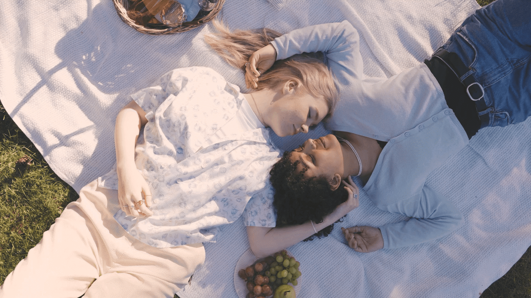 Twee mensen op een picknickkleed, oog in oog, met fruit naast zich.