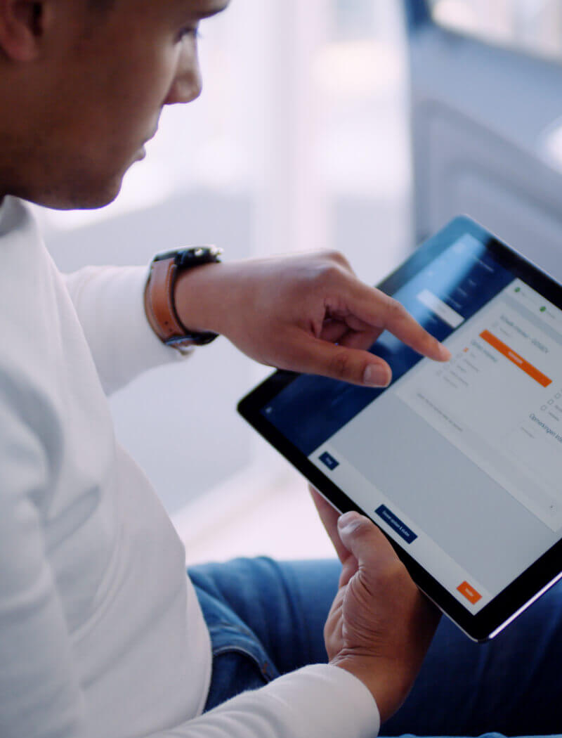 Een persoon in een wit shirt bekijkt zijn Car Collect-lijst op een tablet met oranje accenten.