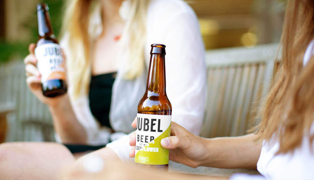 Twee mensen genieten van het moment buiten, met een fris Jubelbiertje in de hand, genietend van de rust en het samenzijn.