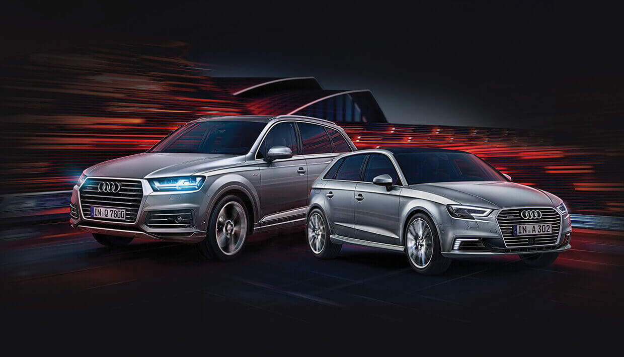 Twee zilveren Audi's geparkeerd naast een moderne Audi Roosendaal, gemarkeerd door opvallende rode lichtstrepen.