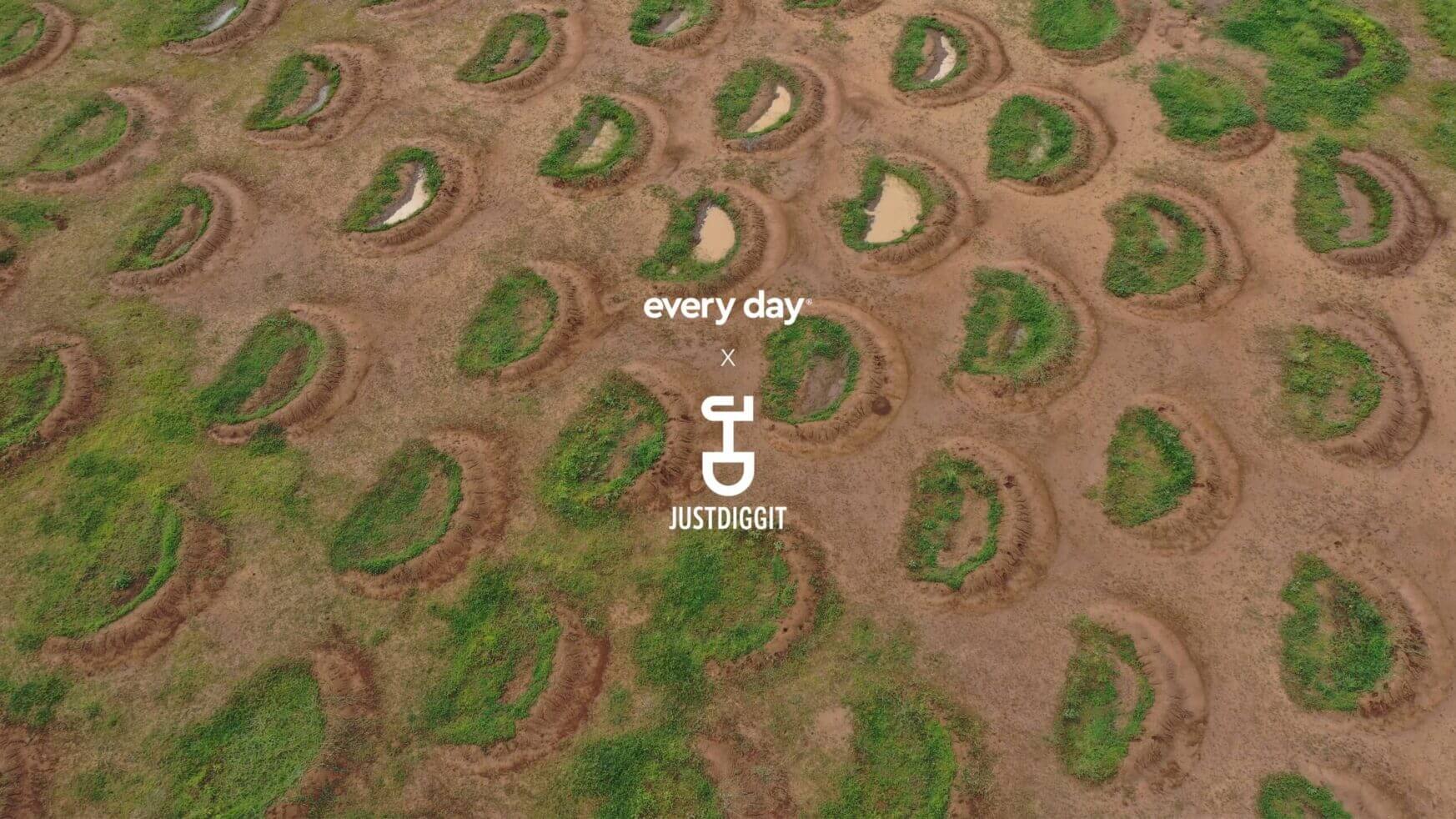 Luchtfoto: Droog terrein bezaaid met groene halve manen en plassen. Tekst: "Every Day" met een scheppictogram.