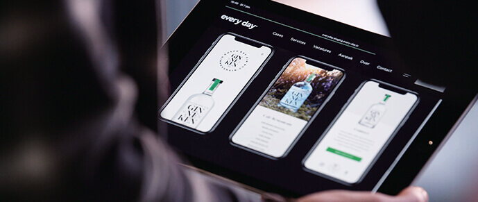 Iemand toont een tablet met een strakke smartphonewebpagina en een fles CAN GIN op de voorgrond.