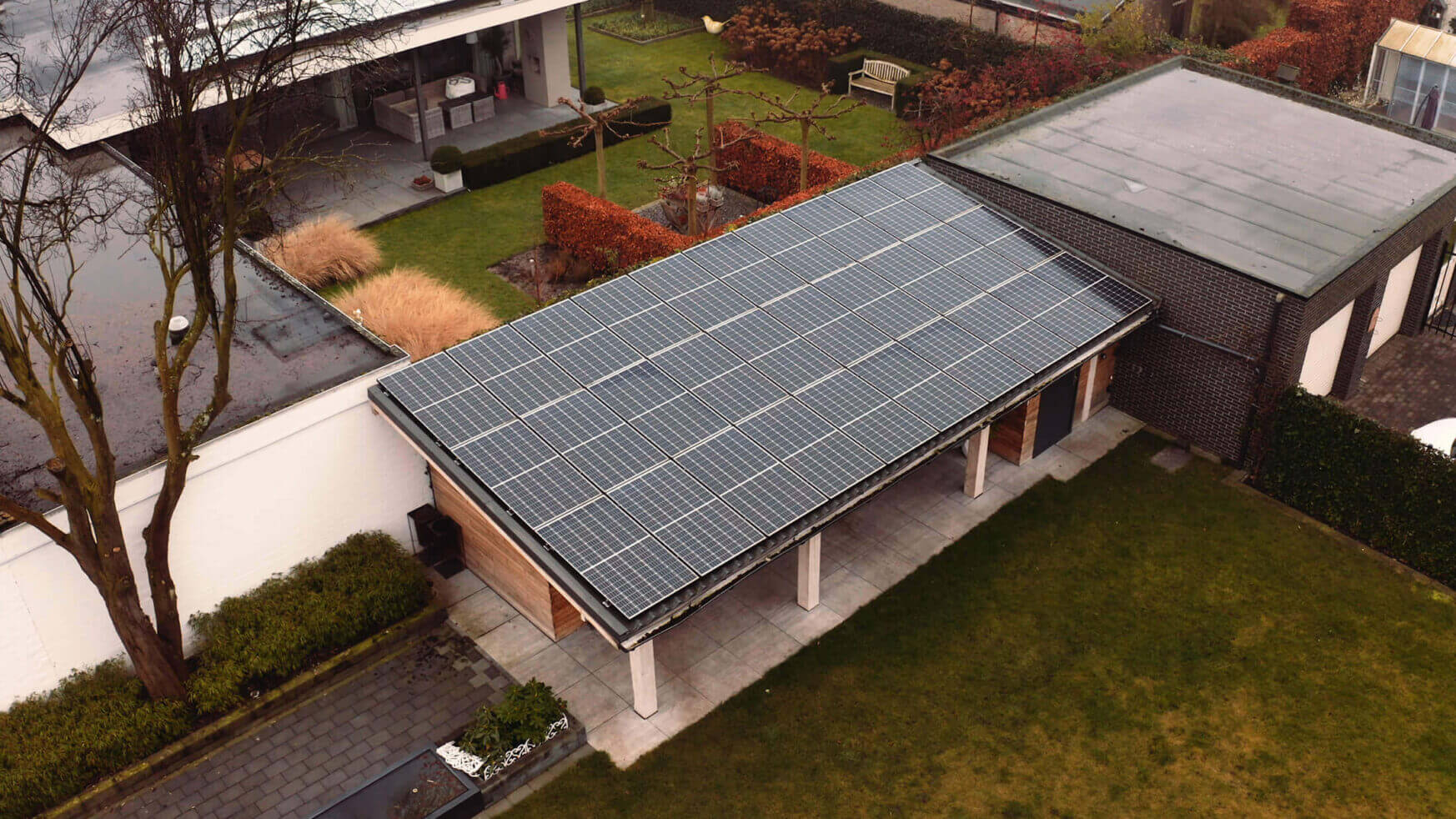 Luchtfoto: YMX Euro Solar-panelen zijn verweven met het dak van een huis, omgeven door weelderige tuinen en bomen.