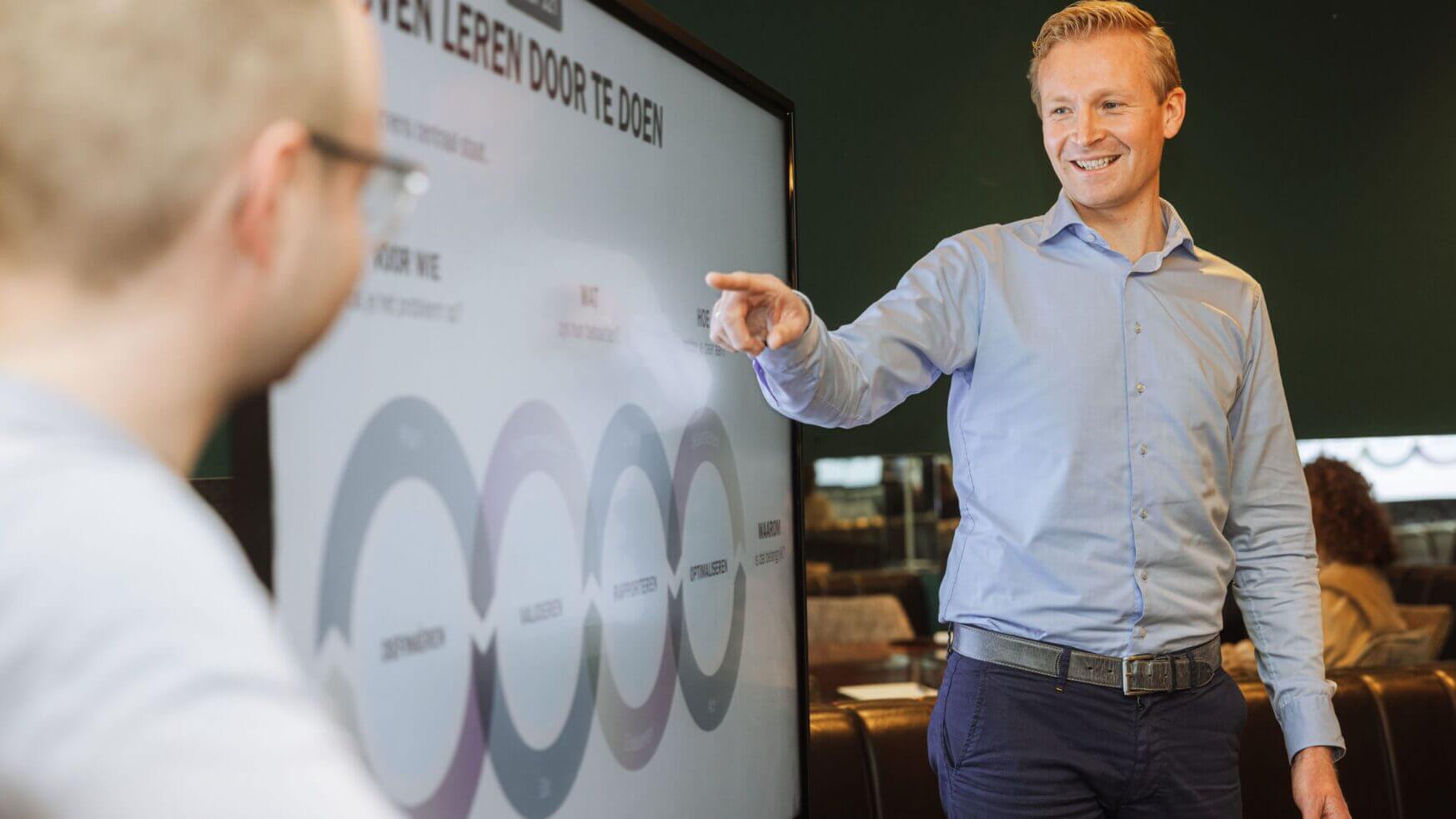 Een vertegenwoordiger van de FIT Group presenteert een kleurrijk diagram terwijl iemand anders aandachtig luistert.
