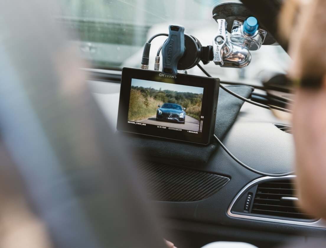 Autodashboard met scherm dat live video toont van een auto die op de weg rijdt. Productie high end.