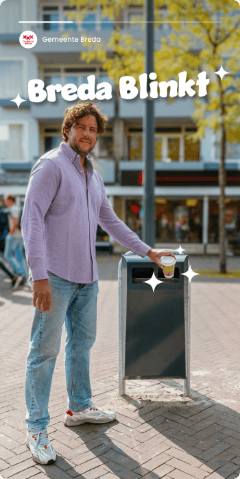 Man gooit koffiekopje in prullenbak, tekst "Breda Blinkt" erboven. Stedelijk straatbeeld, schoon en modern.