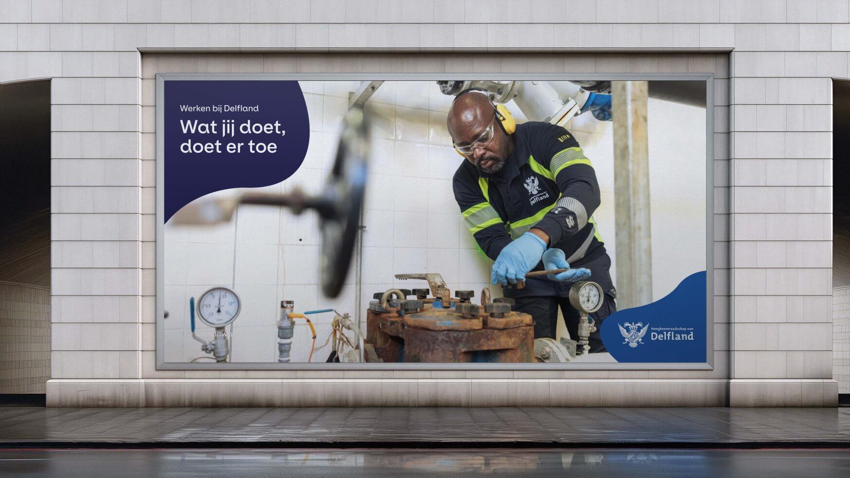 Een man in veiligheidsuitrusting werkt aan industriële apparatuur boven op een Nederlands billboard met het logo van Delfland.