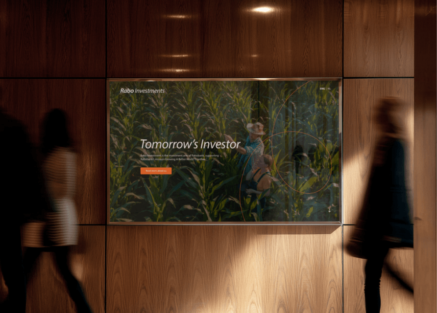 Scherm op houten muur toont "Tomorrows Investor" terwijl mensen wazig voorbij lopen.